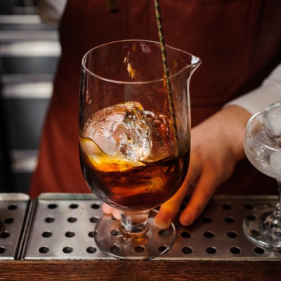 Bartender is stirring cocktails on the bar counter. na face